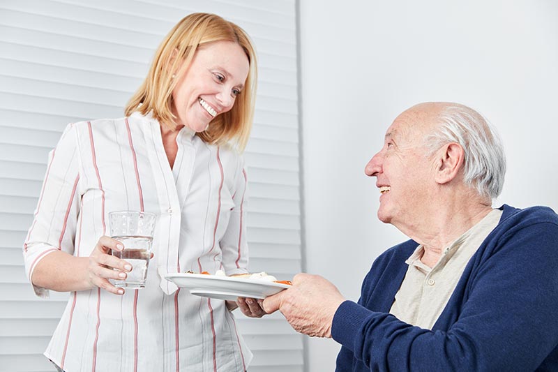 Ein älterer Herr freut sich im Seniorenheim über seine Mahlzeit – denn ansprechend angerichtete Speisen machen auch älteren Menschen Appetit