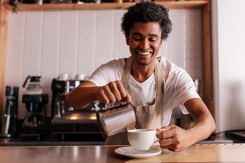 Ein Barista gießt Milchkaffee in eine Tasse 
