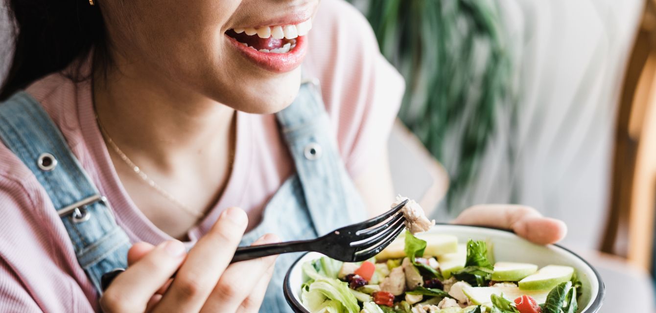 Lächelnde junge Frau isst einen Salat